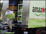  An Amazon Fresh worker delivers groceries in Seattle, where the ecommerce giant has deployed a fleet of 12 trucks to test its new service.  Customers also can pick up grocery orders at certain sites.
