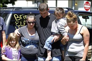 Terry Steinfurth, center, holds his daughter, Kylee Steinfurth, 4, as he prays for missing daughter  Elaina Steinfurth, 1, on Leonard Street. With them Tuesday were, from left, Layla Hungerford, 6; Becky Navaugh, Layla’s mom and Terry’s girlfriend, and Mary Schiewe, Elaina’s aunt.