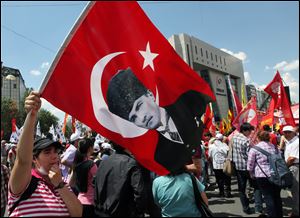 A Turkish protester waves a national flag with a poster of Turkey's founder Kemal Ataturk as thousands of trade union members who are on a two-day strike march to Kizilay Square, city's main center, in Ankara, Turkey, today.