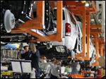  Robert Avelar, Toledo, installs the transmission cooler and radiator hose on a Jeep Liberty at Chrysler's Toledo North Assembly plant.