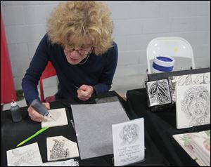 Ottawa Hills artist Barbara Goodman, owner of Ceramigraphix and an art instructor at Owens Community  College, works on a hand-stippled, custom tile at the Toledo Kennel Club Dog Show.  