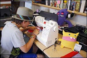 Ben Tollison sews a monster doll at his home in Fort Collins, Colo.