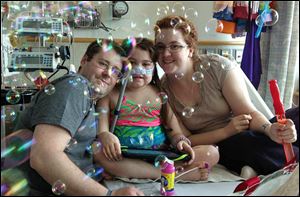 Sarah Murnaghan, center, celebrates the 100th day of her stay in Children's Hospital of Philadelphia Friday, May 30, with her father, Fran, left, and mother, Janet.