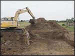  Chet Pieper of Gibsonburg, in the front loader, and Robert Sengstock of Holland, with the surveying stick, dig the foundation for a house at Twin Creek Lane in Sylvania Township. The new-home construction industry, experts say, is growing slowly.