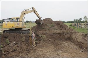 Chet Pieper of Gibsonburg, in the front loader, and Robert Sengstock of Holland, with the surveying stick, dig the foundation for a house at Twin Creek Lane in Sylvania Township. The new-home construction industry, experts say, is growing slowly.