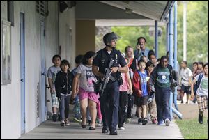 A Santa Monica police officer leads children Friday on a field trip from Citizens of the World Charter School in Los Angeles out of Santa Monica College.