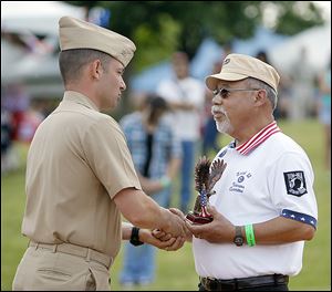 Haraz Ghanbari, left, military and media liaison at the University of Toledo, presents Hector Flores, Sr., of Toledo with an award during the Midwest LatinoFest in Promenade Park on Saturday.