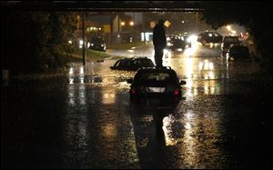 A man stands on top of his car as it is flooded on in Oklahoma City a week ago.