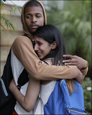 A weeping woman is comforted after being escorted off campus as police swarm Santa Monica City College on Friday.