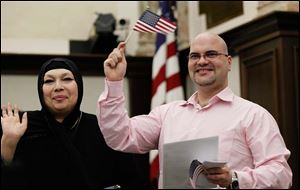 Houda Husamuldeen Albakri and her brother, Omar Albakri, both of Sylvania Township and originally from Iraq, wave to family after becoming U.S. citizens. Their mother, Elham Hasan Salami, also became a citizen during Monday's naturalization ceremony.