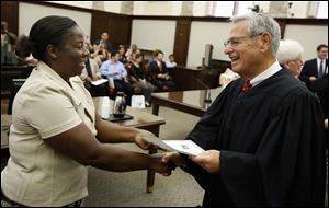 Yar Kiepeeh Davay of Toledo, originally from Liberia, gets her certificate of citizenship from Judge David Katz during a naturalization ceremony in U.S. District Court in Toledo. She and 27 other people became U.S. citizens Monday.