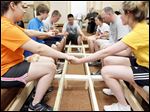  From far left, volunteers Morgan Dunlap, Dillon Novak, Matt Kreutzer, Donovan Novak, Annie Lebert, Mark DeNapoli, and Corinne Muha pray on Tuesday around the ramp they are building before lunch during work at Helping Hands of St. Louis Outreach Center in East Toledo. Hundreds of teenagers from across the nation are donating their time as part of the Catholic HEART Workcamp.