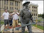  Instructor Thomas Lingeman heats ‘The Hiker’ at the Lucas County Courthouse as part of a UT outdoor sculpture conservation class as students Steven Hoody, Hayley Geyer, and Conor Roberts, from left, wait to begin waxing it.