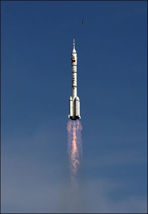 A bird flies as the Long March 2F rocket carrying the Shenzhou 10 capsule blasts off from the Jiuquan Satellite Launch Center in Jiuquan, northwest China's Gansu Province, today.