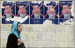 An Egyptian walks past anti-government posters for a campaign calling for the ouster of Egyptian President Mohammed Morsi and for early presidential elections in Cairo, Egypt.