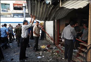 Syrians inspect a damaged shop at a scene of two explosions in the central district of Marjeh, Damascus today.