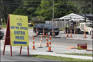 Local businesses remain open as workers with Geddis Paving work on part of Secor Road in West Toledo. The interchanges from Secor to I-475 are also closed.