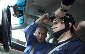 Russ Martin of AAA, is assisted by Joel Cooper, left, hooking the electroencephalographic (EEG)-configured skull cap to the research vehicle during a demonstrations in support of their new study on distracted driving in Landover, Md..