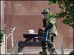  A Toledo police bomb squad member inspects a suspicious package on a table outside One Government Center.