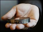  Patty James, the University of Toledo director of senior administrative operations, holds the POW bracelet, which reads: ‘Col. Lawrence Guarino 6-14-65.’ 