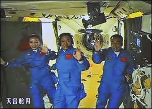 In this image made off the screen at the Beijing Aerospace Control Center and released by China's Xinhua News Agency, Chinese astronauts, from left, Wang Yaping, Zhang Xiaoguang and Nie Haisheng, wave inside the Tiangong-1 space module Thursday.