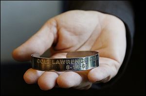 Patty James, the University of Toledo director of senior administrative operations, holds the POW bracelet, which reads: ‘Col. Lawrence Guarino 6-14-65.’ 