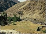  India and Pakistan come face to face in hostile posture in Kashmir. The small grassy knoll in the middle is no man's land. The famous Lasa-Skardu trail is half-way up the mountain on the right.
