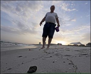 A small shell is embedded in a tar ball on the beach in Gulf Shores, Ala. After three years and $14 billion worth of work following the BP oil spill in the Gulf of Mexico, the petroleum giant and the Coast Guard say it's time to end extraordinary cleanup operations in Alabama, Florida and Mississippi.