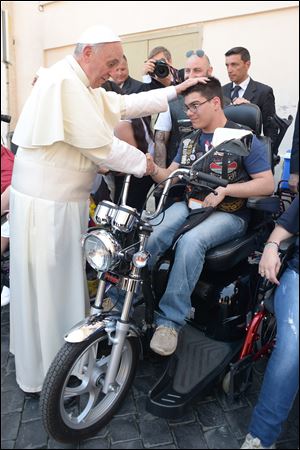 Pope Francis blesses a man in Harley-Davidson garb while spending time chatting with sick and disabled persons after the Mass in St. Peter’s Square.