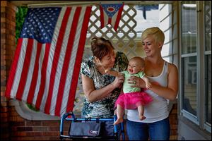 Sandra Vollmar, left, and Swanton resident Alexa Albring hold Ms. Albring's daughter, Aubri Berfield, 6 months, at Mrs. Vollmar's home in South Toledo. Ms. Vollmar was babysitting Aubri last month when she was struck by a hit-and-run driver. She managed to save the infant from injury.