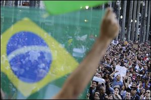 A demonstrator holds up a Brazilian flag in front of a group of protestors gathered in the main plaza of Sao Paulo, Brazil, Tuesday.
