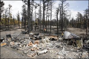 Firefighters are pictured beyond a burned structure as they work hot spots on the Black Forest wildfire north of Colorado Springs, Colo., on Monday.
