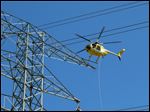  Gordon Winfree of Winco, Inc., piloting helicopter, rigs rope onto a block on a FirstEnergy tower in rural Sandusky County near Fremont Wednesday.