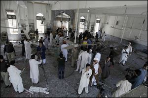 People gather at a Shiite mosque targeted by a suicide bomber in Peshawar, Pakistan on Friday. Militants opened fire on a Shiite Muslim mosque where worshippers were gathering for prayers, and then a suicide bomber detonated his explosives inside, killing more than a dozen people.