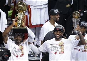 The Miami Heat's Dwyane Wade, left, holds the Larry O'Brien NBA Championship Trophy as  LeBron James holds his Bill Russell NBA Finals Most Valuable Player Award.