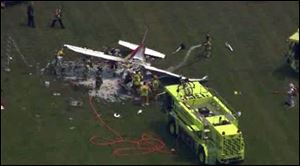 This frame grab from video provided by WDIV, WJBK, and WXYZ, shows emergency personnel examining a plane crash after a pilot and three passengers were killed shortly after takeoff.