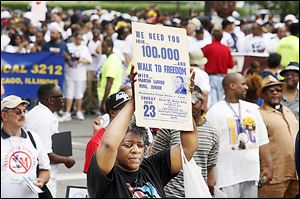 An original sign from the June 23, 1963, 'Walk to Freedom' is held high during Saturday's march in Detroit. 
