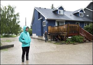 A woman looks over the water damage from her back yard in the flooded community of Bowness.