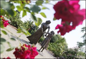 A sculpture of a mother and child stands in the Rose Garden in the Toledo Botanical Garden.