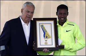 Boston Marathon 2013 men's winner Lelisa Desisa, right, of Ethiopia, holds his medal with Boston Mayor Thomas Menino after presenting it to the city as a tribute to the victims of the Boston Marathon bombings, Sunday.