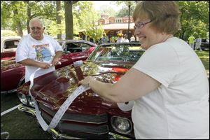 Larry Youngs and his wife, Karen Youngs, measure a roll of 50/50 raffle tickets around the length of a car for a customer. The raffle supports A Special Wish Foundation Inc. 