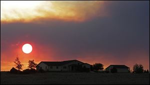 The sun sets through wildfire smoke near Monte Vista, Colo. 
