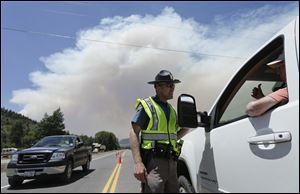 Colorado State Patrol officer Jessie Bartunek talks to a motorist as he stands at a checkpoint near South Fork, Colo.