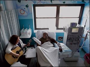 Sarah Tobias plays music for dialysis patient Chris Blackwell, 19, at Akron Children's Hospital.