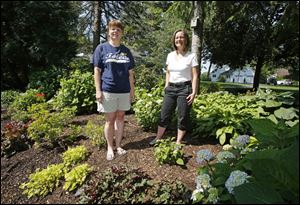 Amy Stolarski, left, and Lyn Tucholski pose in the shared garden between their front yards on Obee Road in Monclova Township.