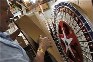 Willis Smith, 81,  shows a gaming wheel he made himself. He built many of the wheels supplied by his and his wife’s company because he was unhappy with the quality of those available for purcahse.  out a gaming wheel he hand-made. He and his wife Elaine, 79, are retiring after nearly 40 years of owning and operating their business, Toledo Central Distributors. The pair, who raised eight children in Toledo, say the best part of their business has been working with customers. They have supplied hand made games and amusements for schools, churches and carnivals. Willis built many of the company's attractions by hand, including the hand-carved and hand-painted gaming wheels, after he realized those available for purchase were of poor quality.