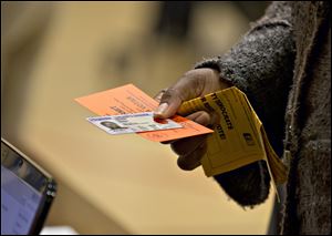 A voter holds their voting permit and ID card at the Washington Mill Elementary School near Mount Vernon, Va., in 2012.