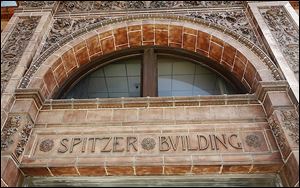 An auction for the 10-story Spitzer Building at 520 Madison Ave. has been delayed by a bankruptcy filing, but officials say the building will continue operating as it has been.