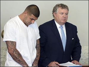 Former New England Patriots tight end Aaron Hernandez, left, stands with his attorney Michael Fee, right, during arraignment in Attleboro District Court Wednesday, in Massachusetts. Hernandez was charged with murdering Odin Lloyd, a 27-year-old semi-pro football player.