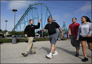 John Hoiden, Department Supervisor for Rides at Cedar Point amusement park in Sandusky, helps a family locate the ride they are looking for on a map, while walking through the park.